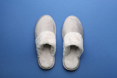 Photo of Pair of soft slippers on blue background, flat lay