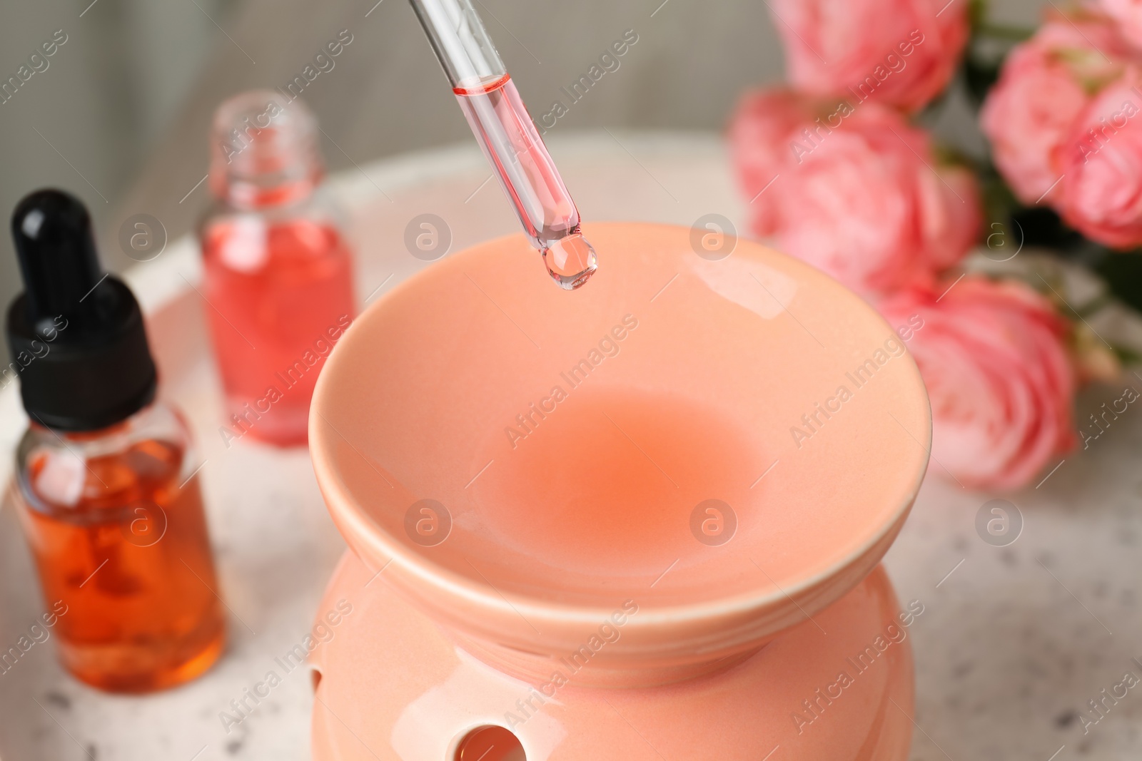 Photo of Dripping essential oil into aroma lamp on white tray, closeup