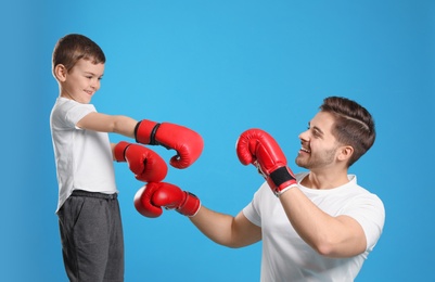 Dad and his son with boxing gloves on color background