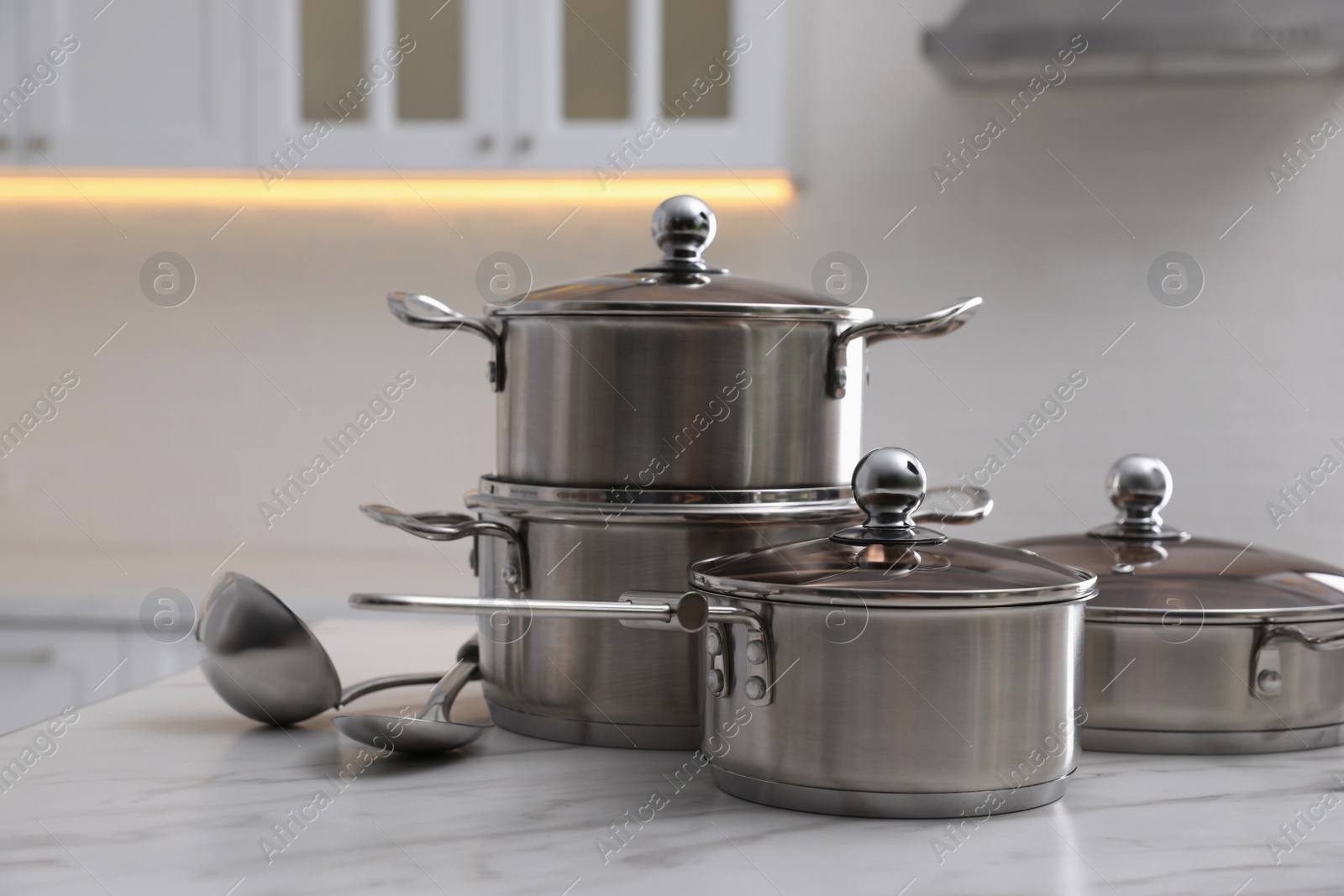 Photo of Set of new clean cookware and kitchen utensils on white marble indoors