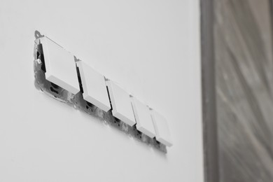 Photo of Modern plastic switches on white wall indoors, low angle view