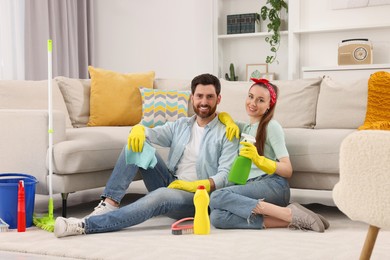 Photo of Spring cleaning. Couple with detergents and mop in living room