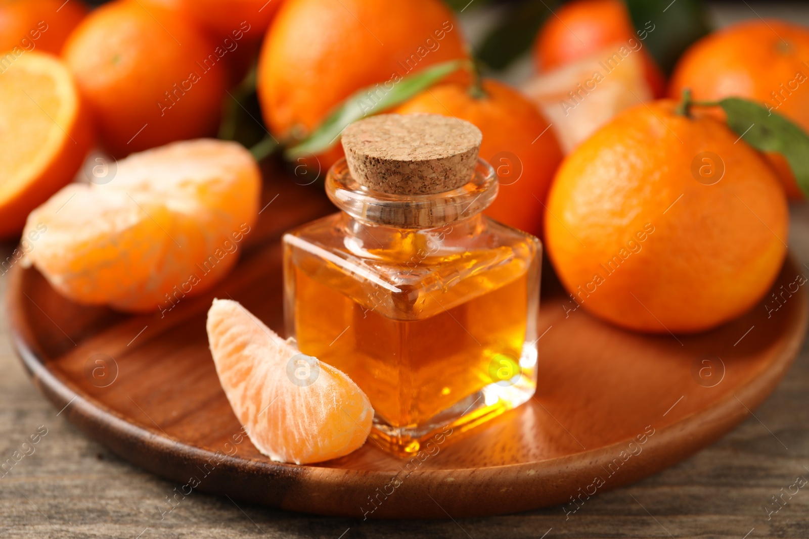 Photo of Bottle of tangerine essential oil and fresh fruits on wooden table