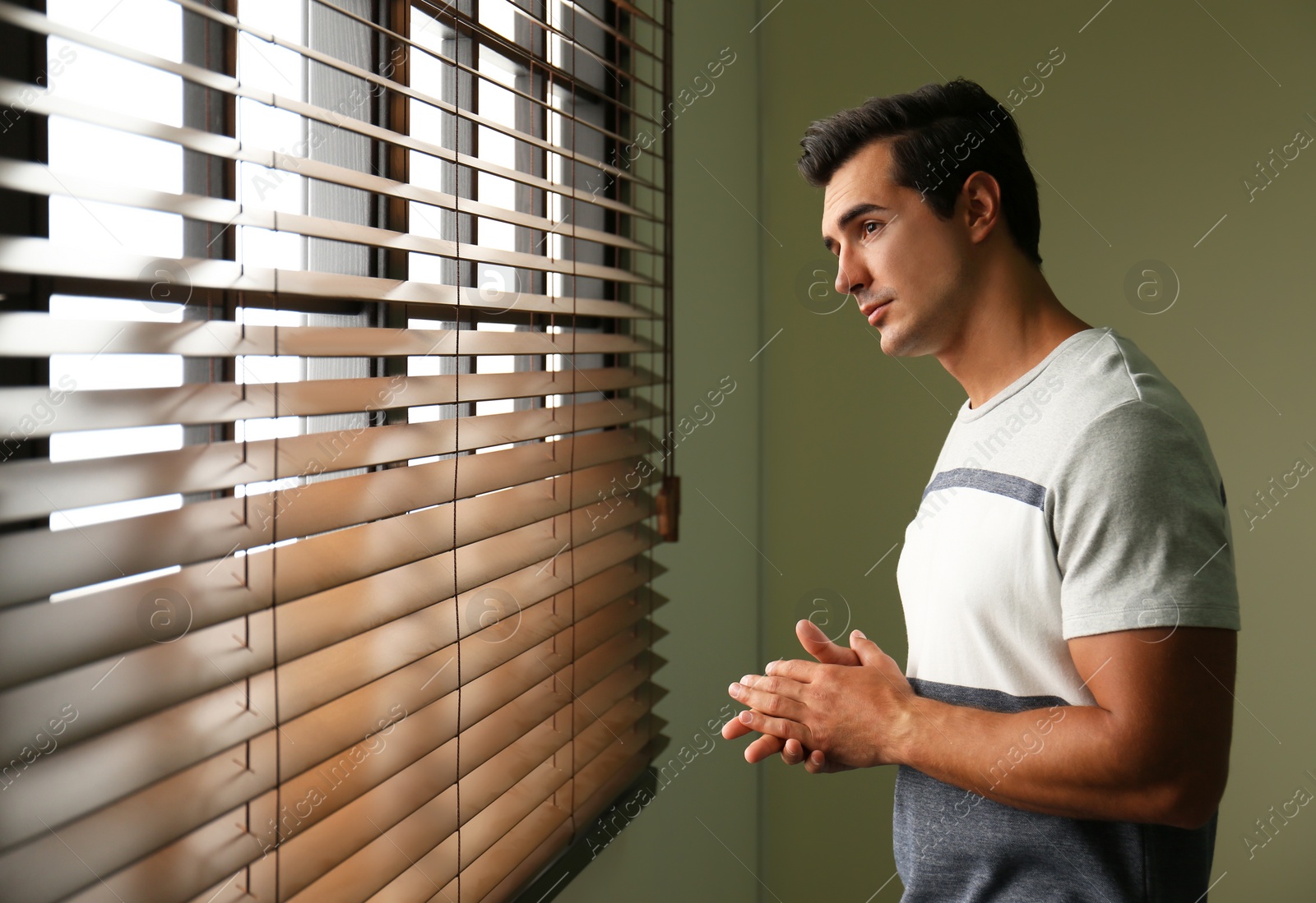 Photo of Handsome young man looking out window indoors