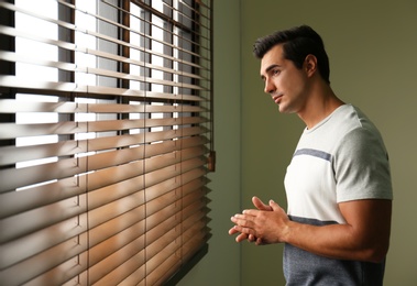 Photo of Handsome young man looking out window indoors