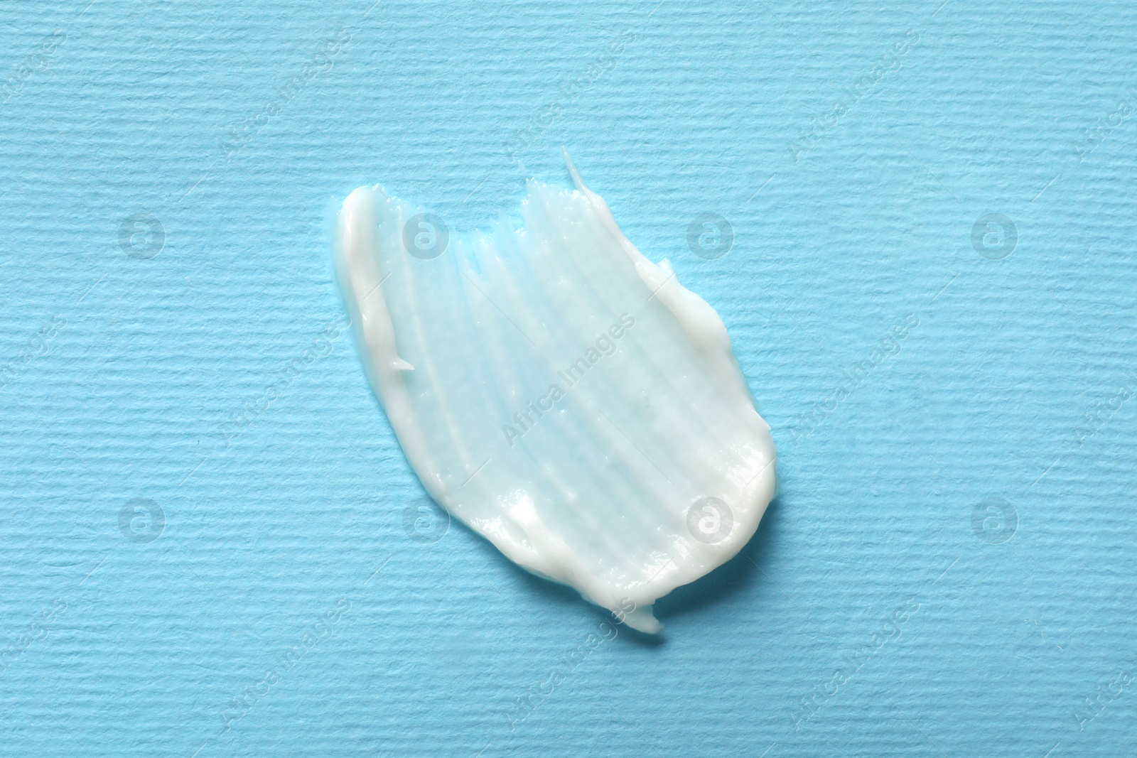 Photo of Smear of ointment on light blue background, top view