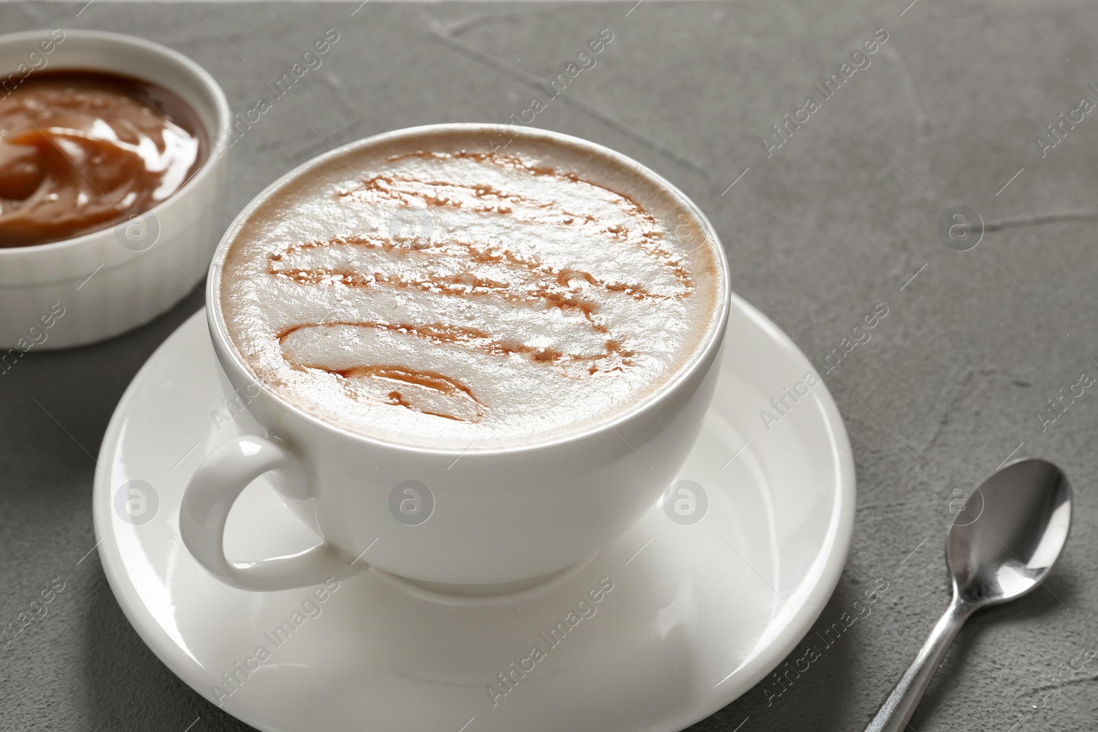 Photo of Cup of tasty caramel macchiato and syrup on table