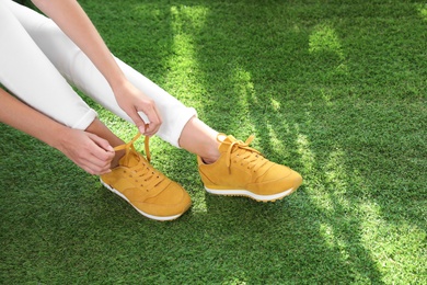 Photo of Young woman wearing stylish sneakers on green grass, closeup