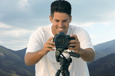 Image of Photographer with professional camera and beautiful view of mountains on background