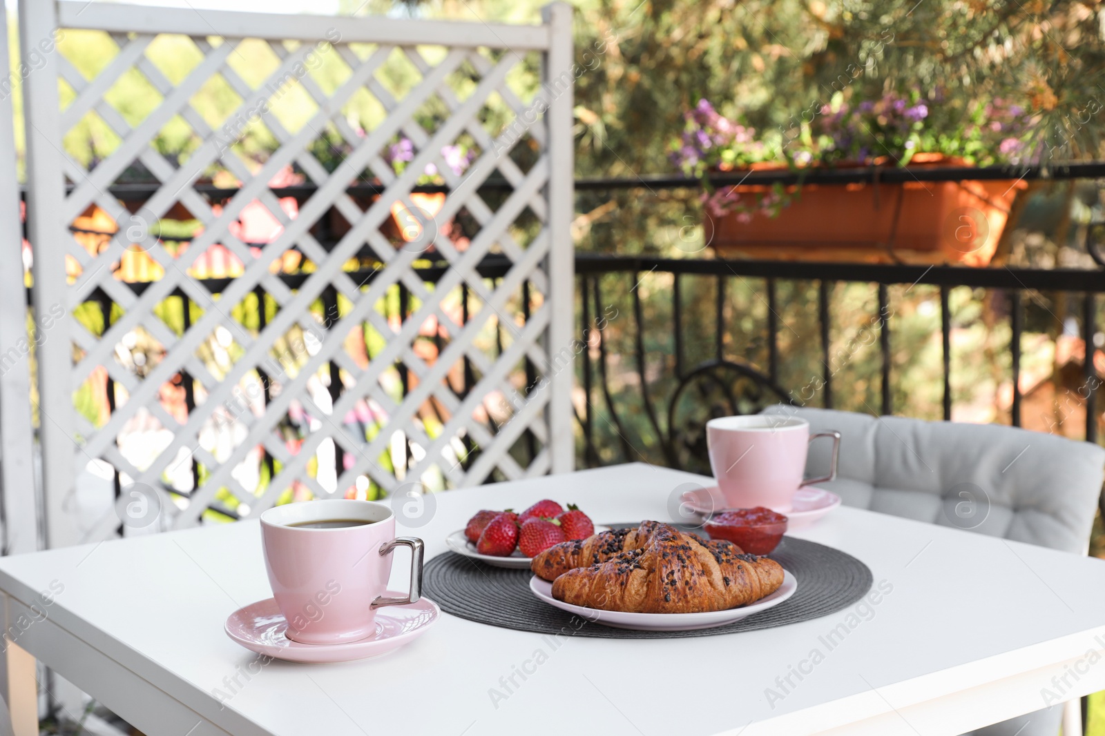 Photo of Outdoor breakfast with tea and croissants on white table on terrace