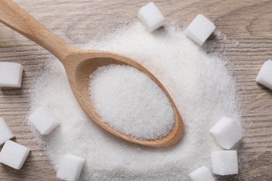 Photo of Different types of white sugar and spoon on wooden table, top view