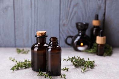 Thyme essential oil on light grey table, space for text