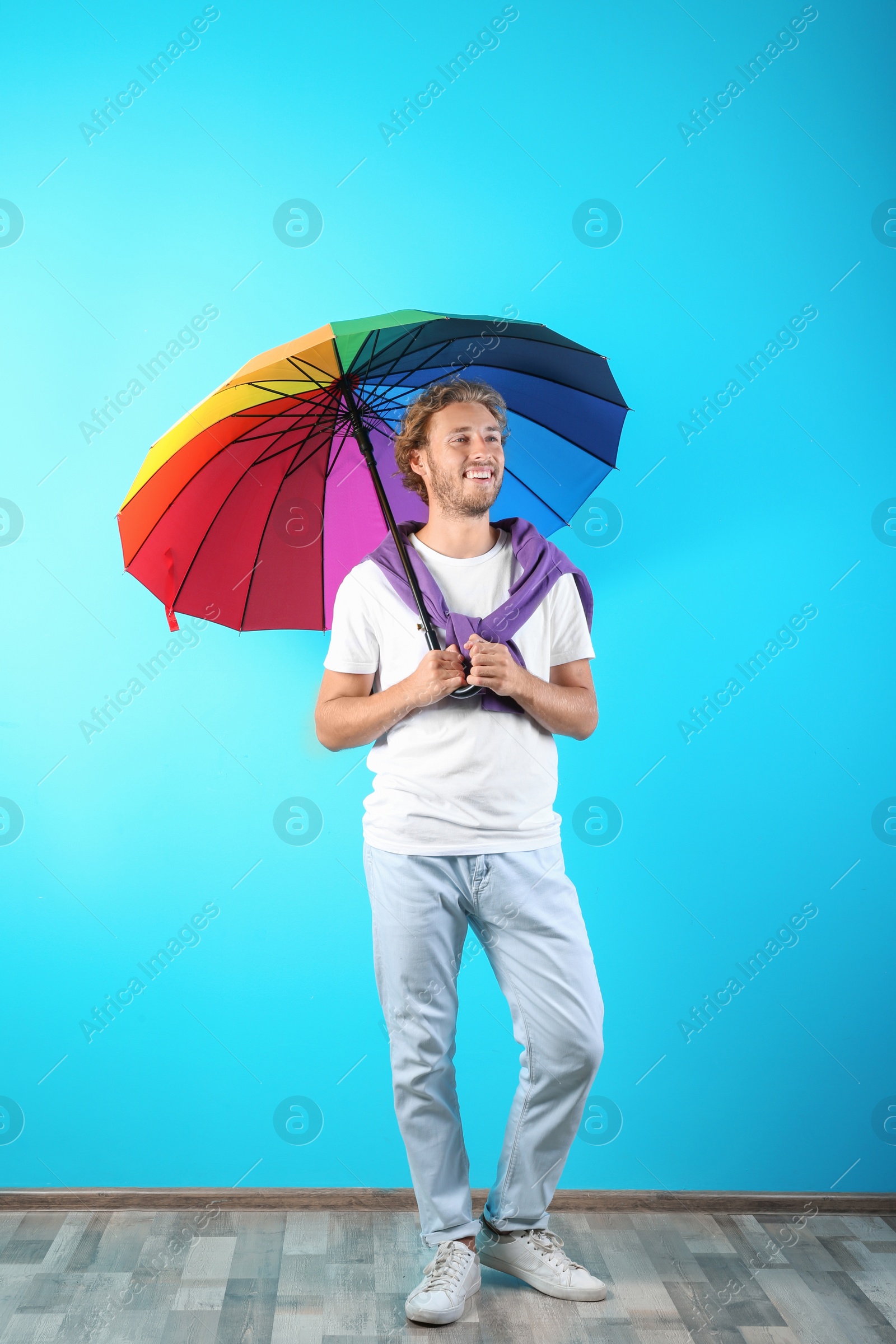 Photo of Man with rainbow umbrella near color wall