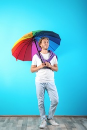 Man with rainbow umbrella near color wall