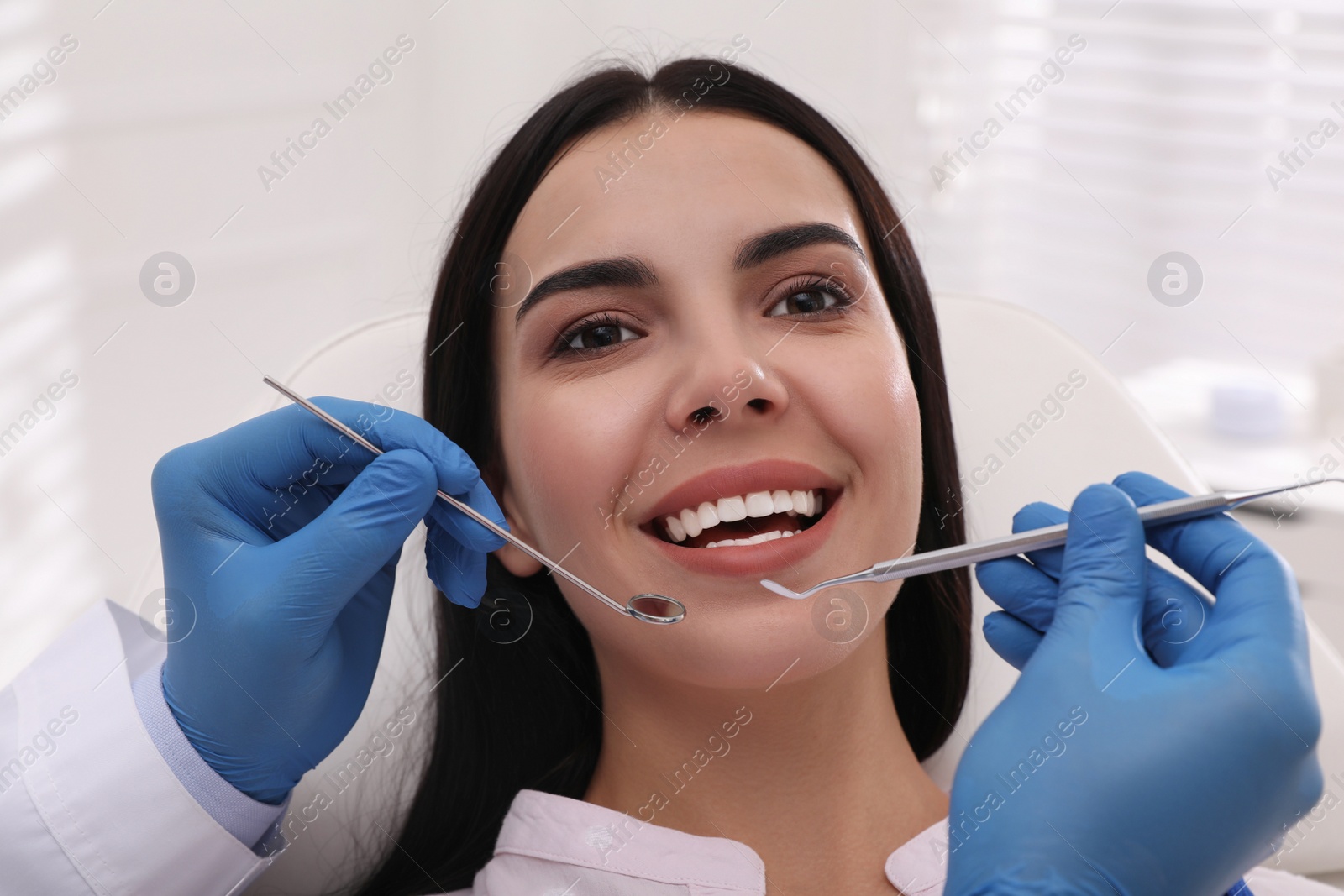 Photo of Dentist examining young woman's teeth in modern clinic