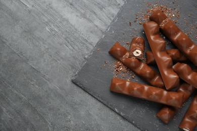 Photo of Tasty chocolate bars with nuts on black table, top view. Space for text