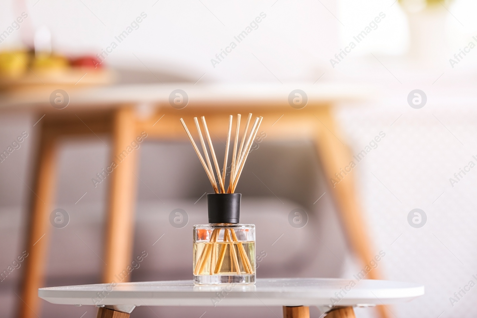 Photo of Aromatic reed air freshener on table against blurred background