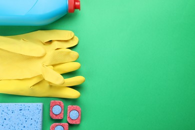 Flat lay composition with dishwasher detergent pods and tablets on green background, space for text