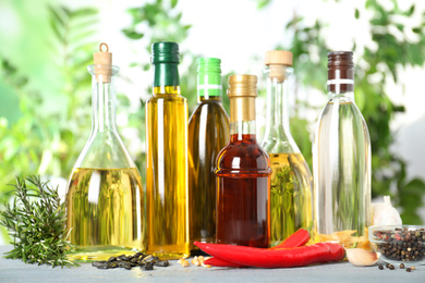 Photo of Different sorts of cooking oil in bottles and ingredients on white wooden table