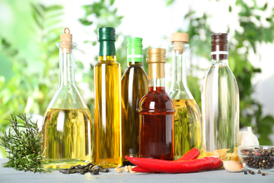 Different sorts of cooking oil in bottles and ingredients on white wooden table