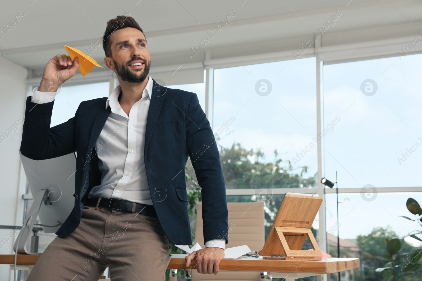 Photo of Handsome businessman playing with paper plane in office