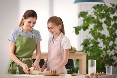 Photo of Mother and her daughter preparing dough at table in kitchen