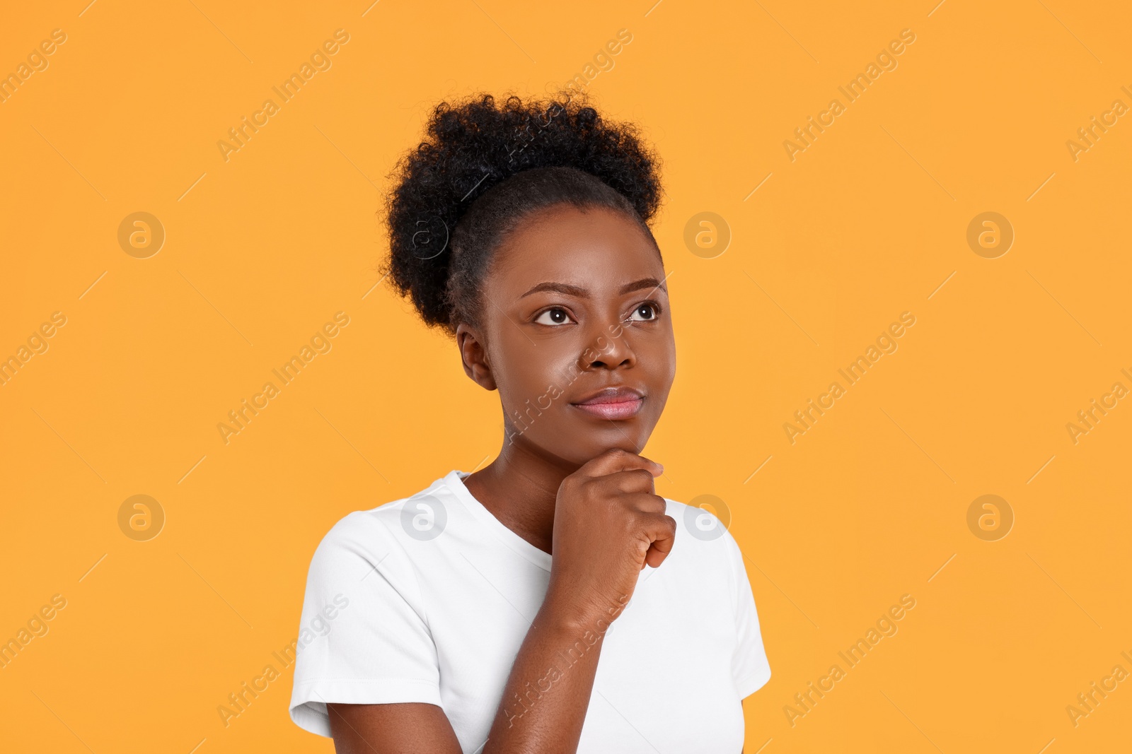 Photo of Portrait of thoughtful young woman on orange background