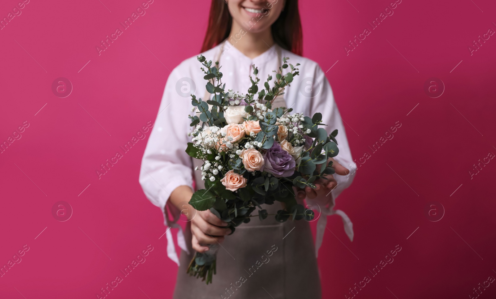 Photo of Florist holding beautiful wedding bouquet on pink background, closeup