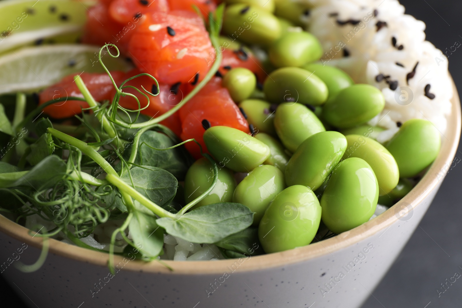 Photo of Delicious poke bowl with lime, fish and edamame beans, closeup view