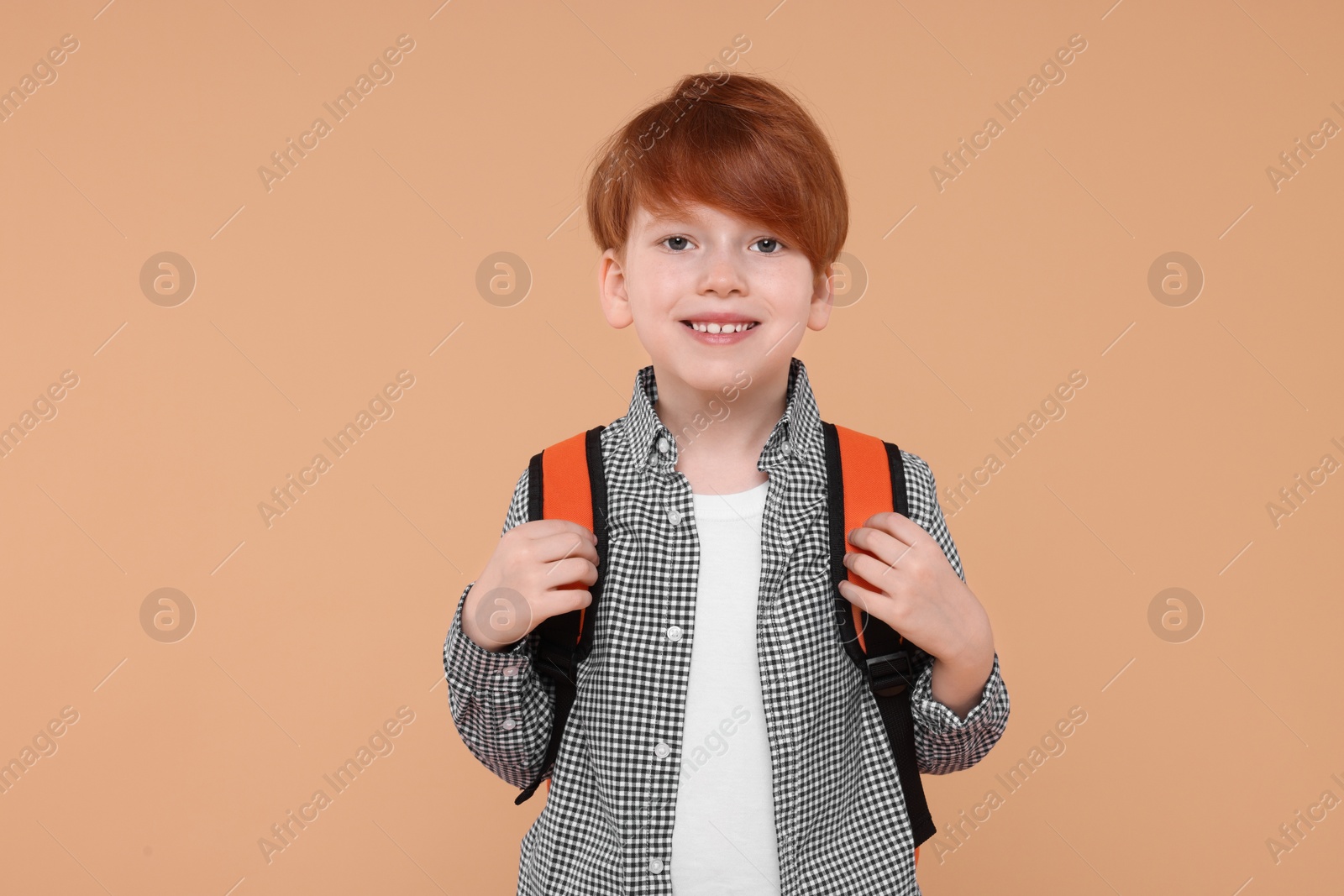 Photo of Portrait of happy schoolboy on beige background