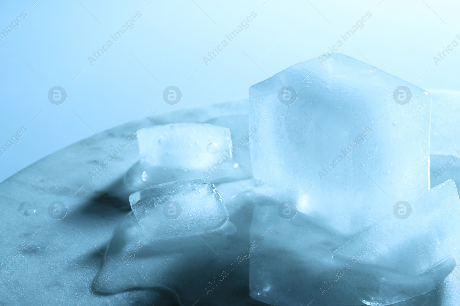 Photo of Crystal clear ice cubes on marble board, color tone effect