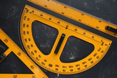 Photo of Protractor, ruler and triangle on blackboard, flat lay