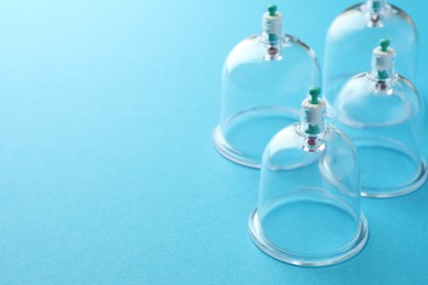 Photo of Plastic cups on light blue background, closeup with space for text. Cupping therapy