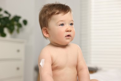 Photo of Cute little baby with moisturizing cream on body indoors