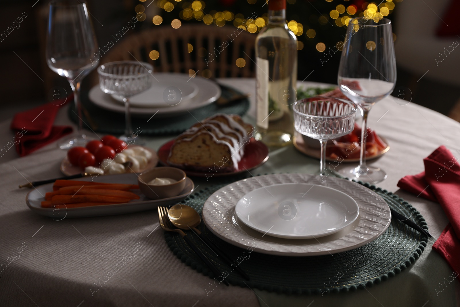 Photo of Christmas table setting with bottle of wine, appetizers and dishware