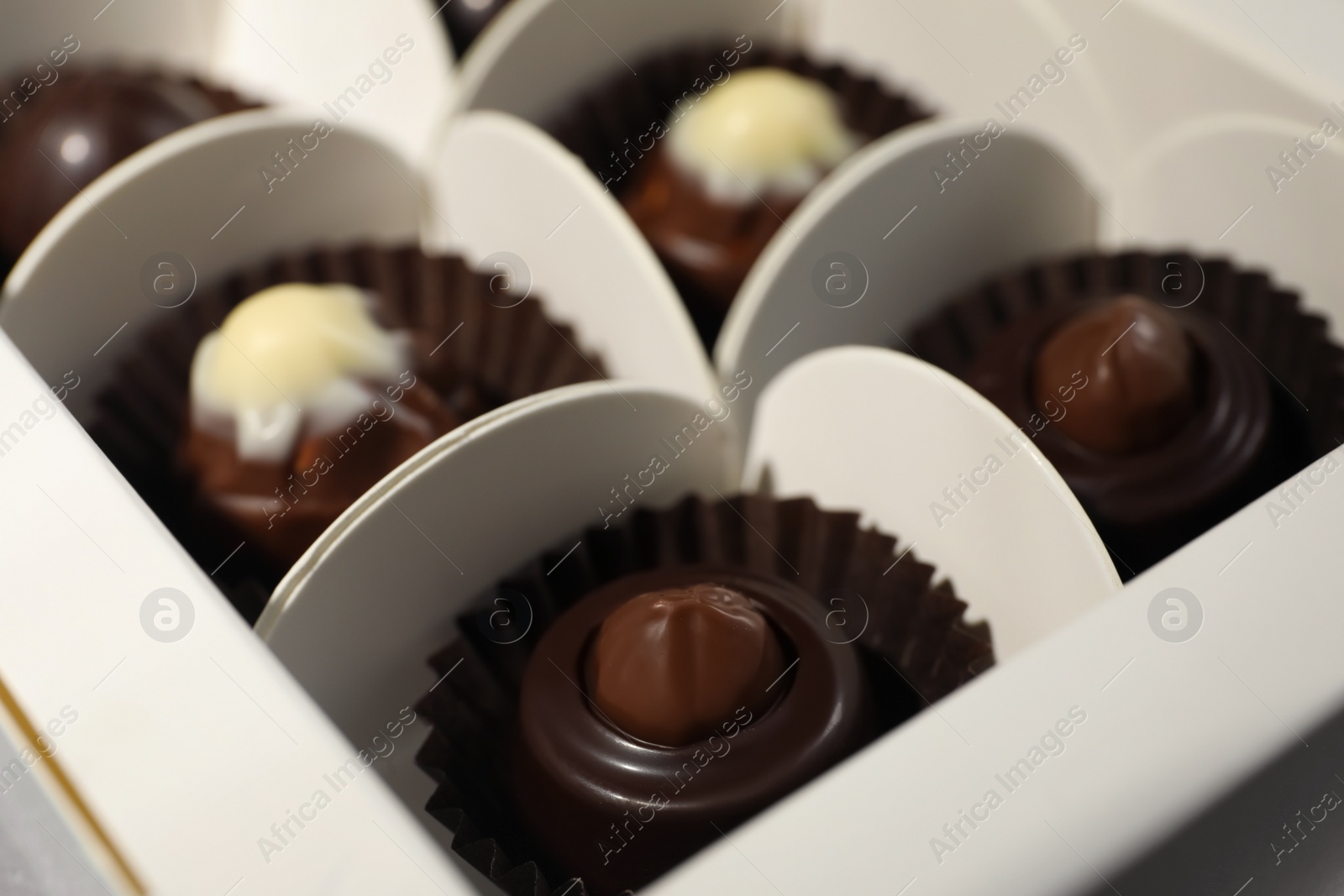 Photo of Many delicious chocolate candies in box, closeup