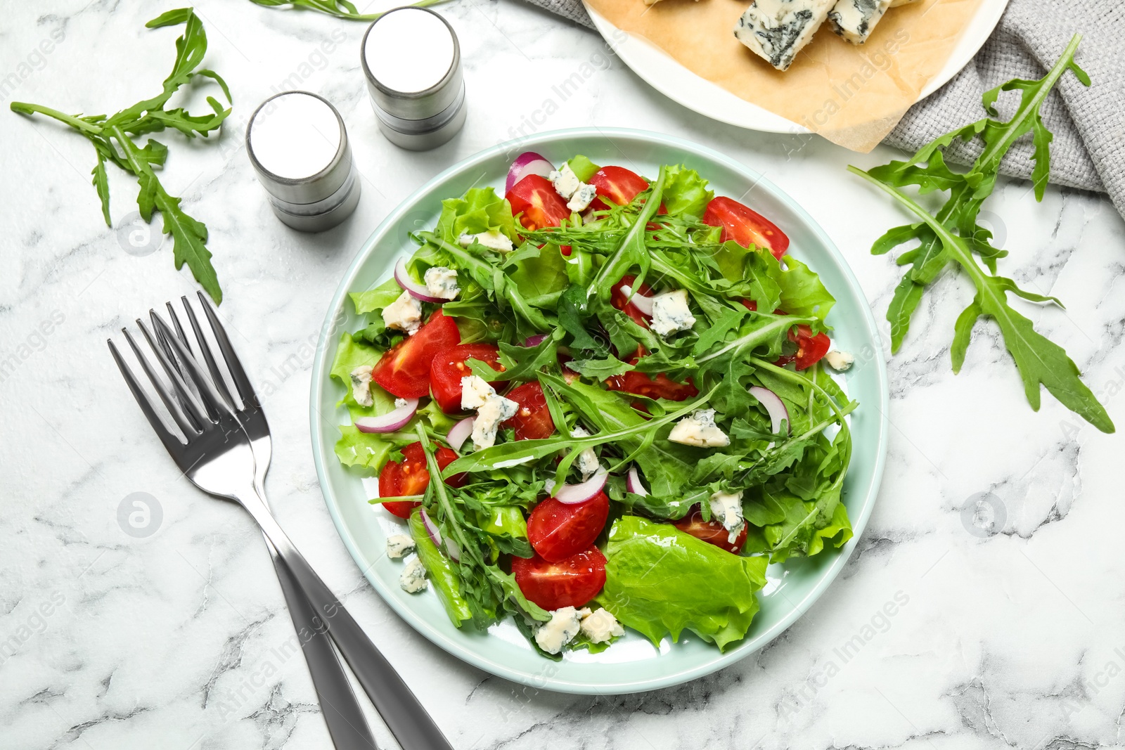 Photo of Delicious salad with arugula and tomatoes on white marble table, flat lay