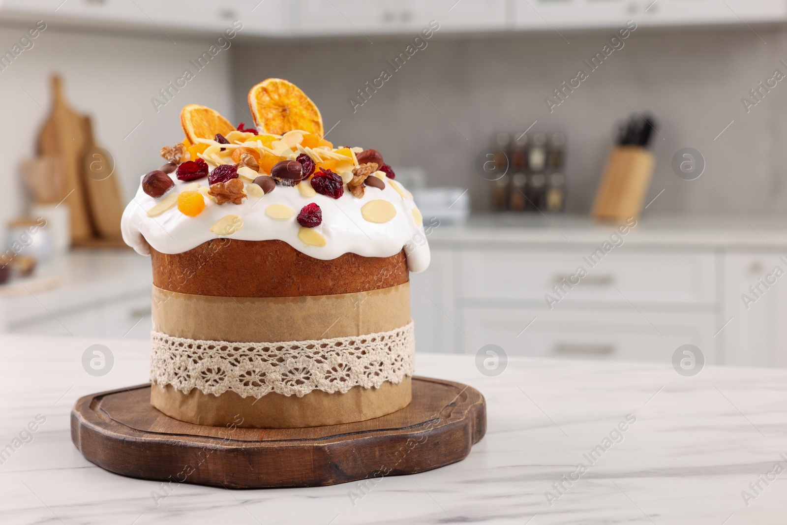 Photo of Delicious Easter cake with dried fruits on white marble table in kitchen. Space for text