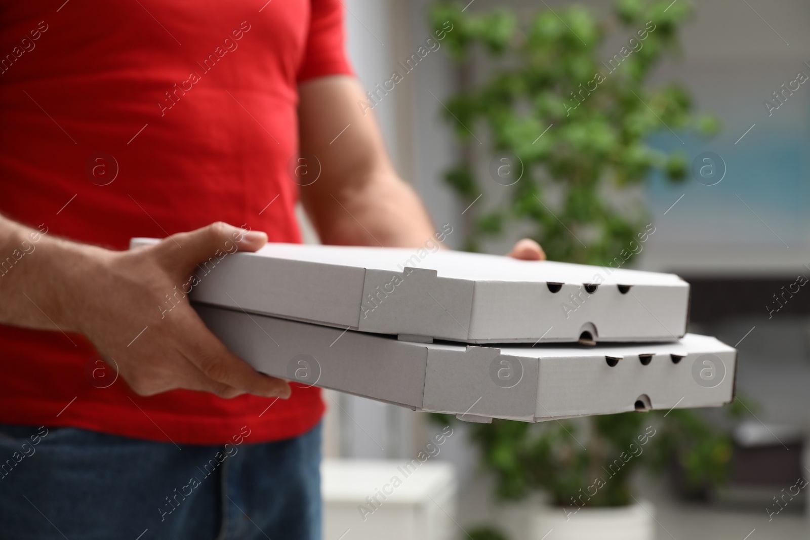 Photo of Courier with pizza boxes on blurred background, closeup