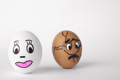 Photo of Eggs with drawn faces on white background. Concept of jealousy