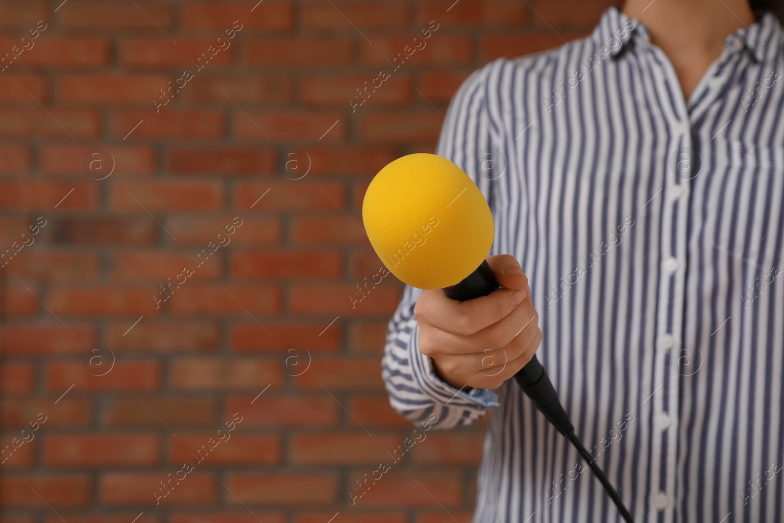 Photo of Journalist with microphone near brick wall, closeup. Space for text