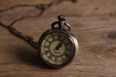 Photo of Pocket clock with chain on wooden table, closeup