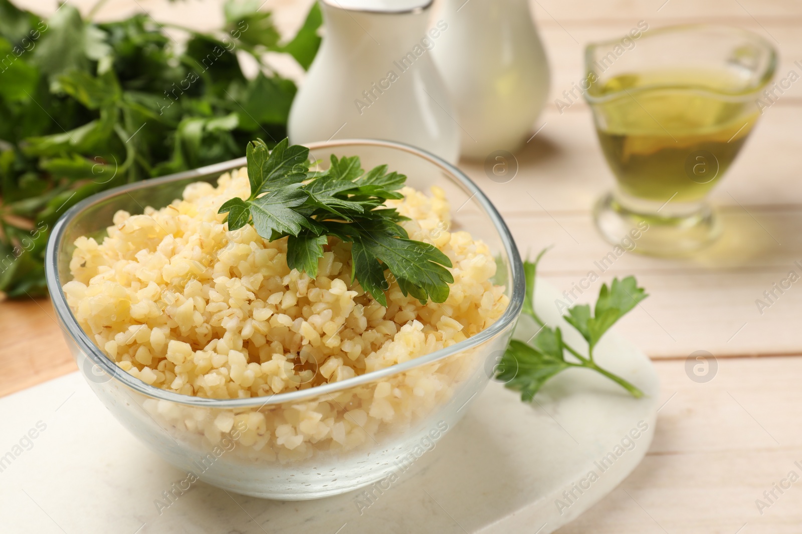 Photo of Delicious bulgur with parsley in bowl on table, closeup