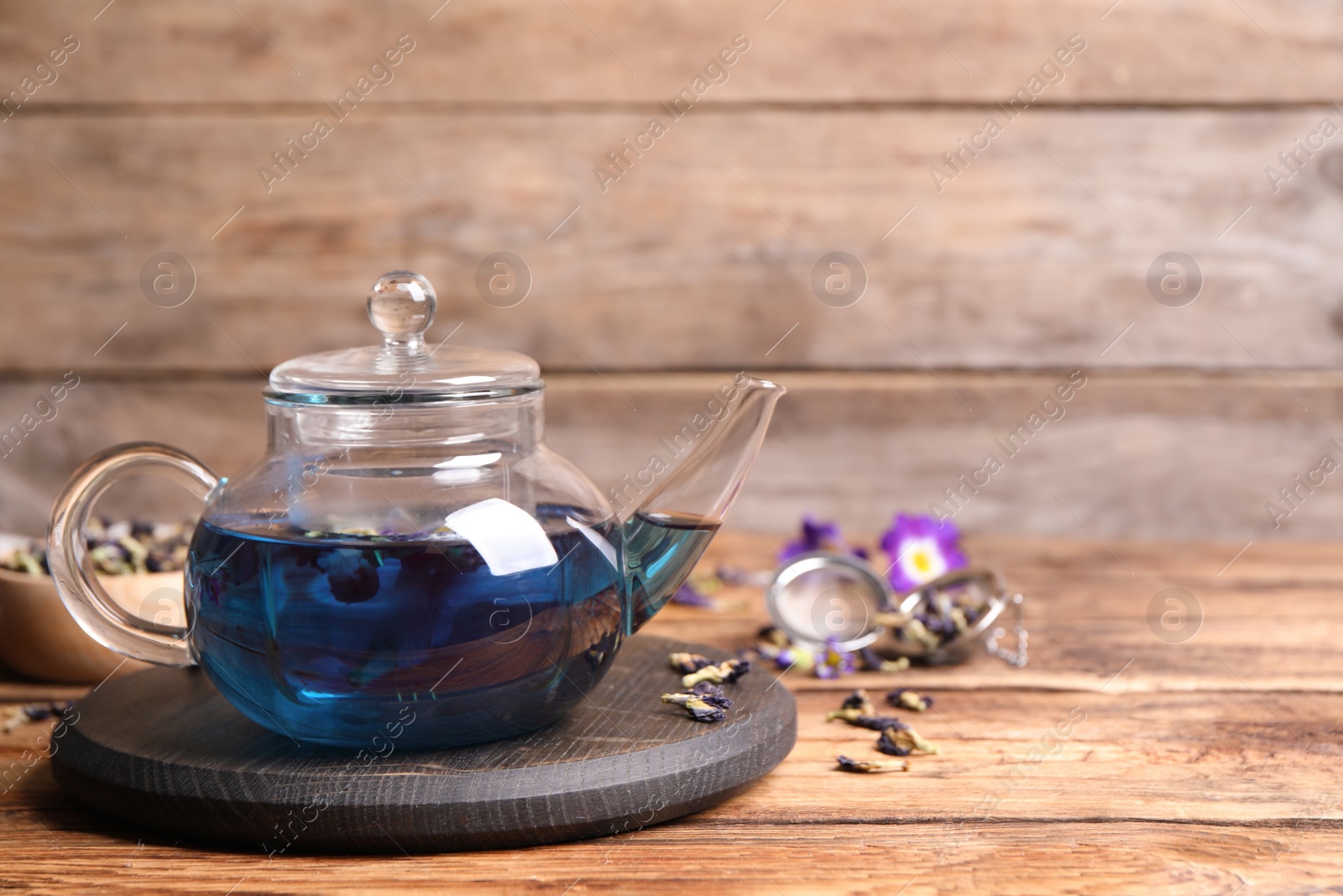 Photo of Organic blue Anchan in glass pot on wooden table, space for text. Herbal tea