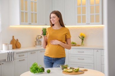 Photo of Young pregnant woman with smoothie in kitchen. Healthy eating