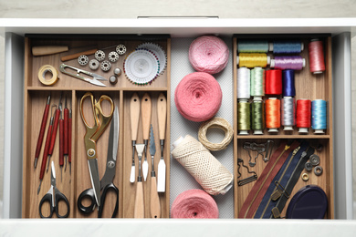 Photo of Sewing accessories in open desk drawer, top view
