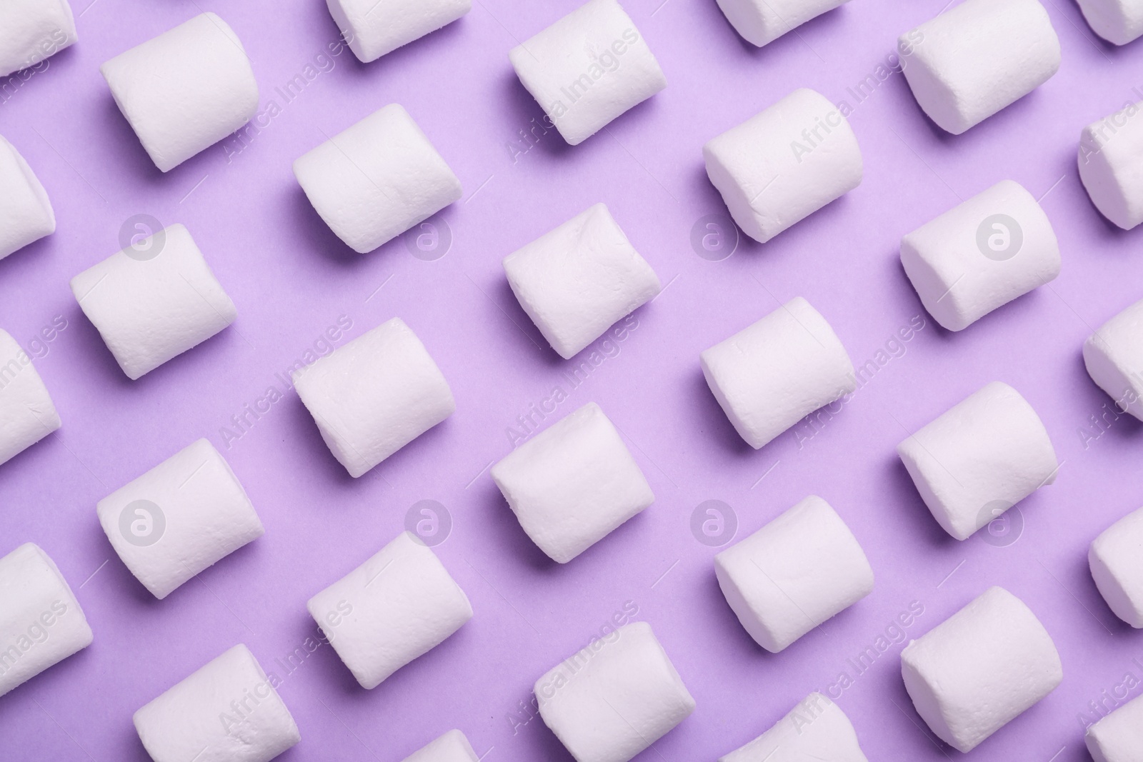 Photo of Delicious puffy marshmallows on lilac background, flat lay
