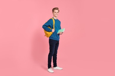 Photo of Teenage boy with books and backpack on pink background
