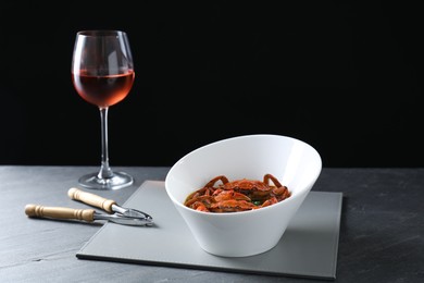 Photo of Delicious boiled crabs, glass of wine and cracker on grey table, space for text