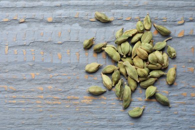 Photo of Pile of dry cardamom pods on grey wooden table, top view. Space for text